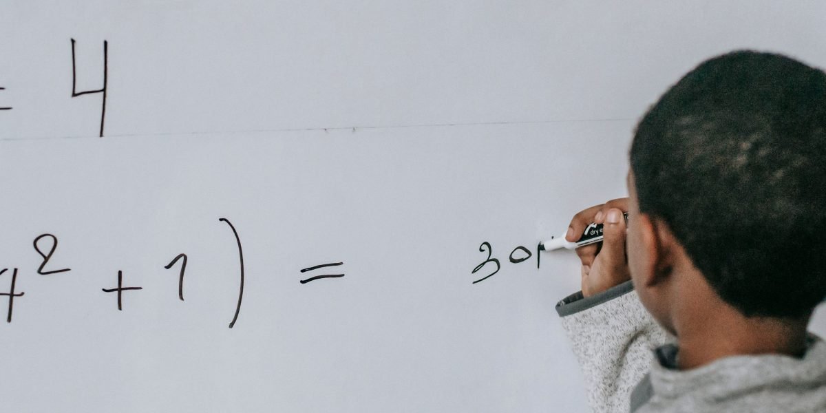 A person actively working on solving a problem, using a whiteboard to demonstrate the hands-on practice needed for cybersecurity skills.