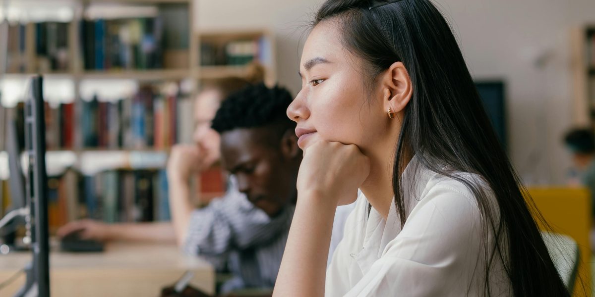 A student researcher is deep in thought while reviewing documents, contemplating the ethical use of AI in their studies.