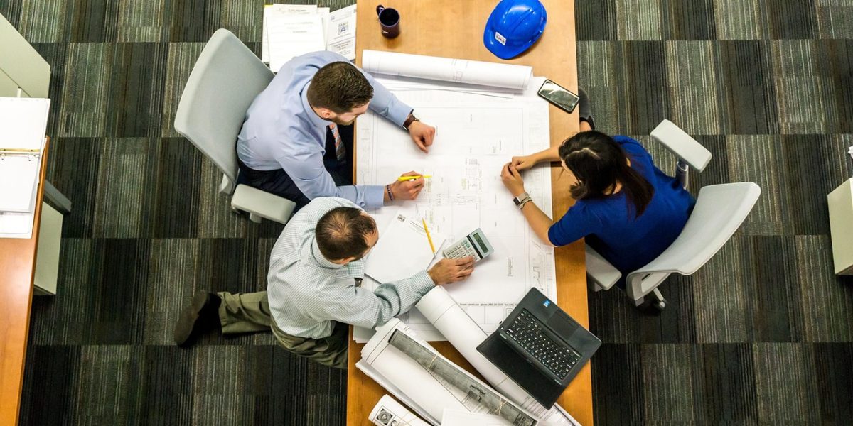 A team collaborating around a table with a large blueprint, representing the foundational work of data modeling.