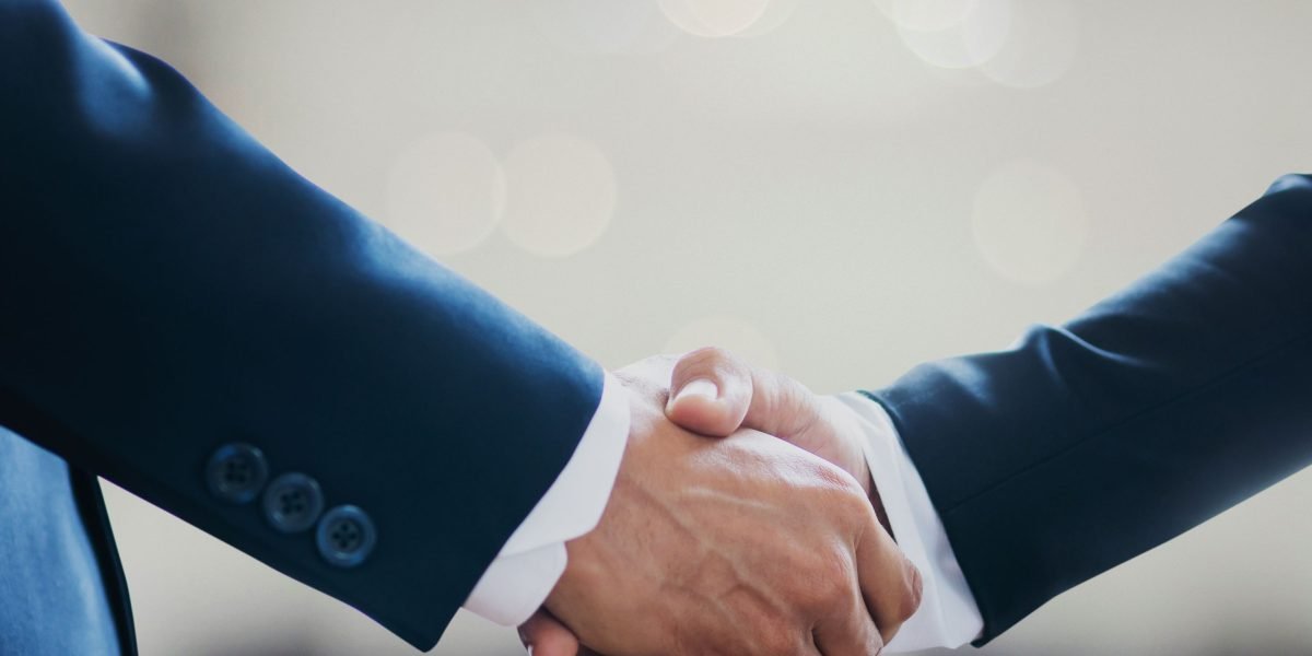 Two professionals shaking hands, symbolizing trust, partnership, and a defensible business approach.