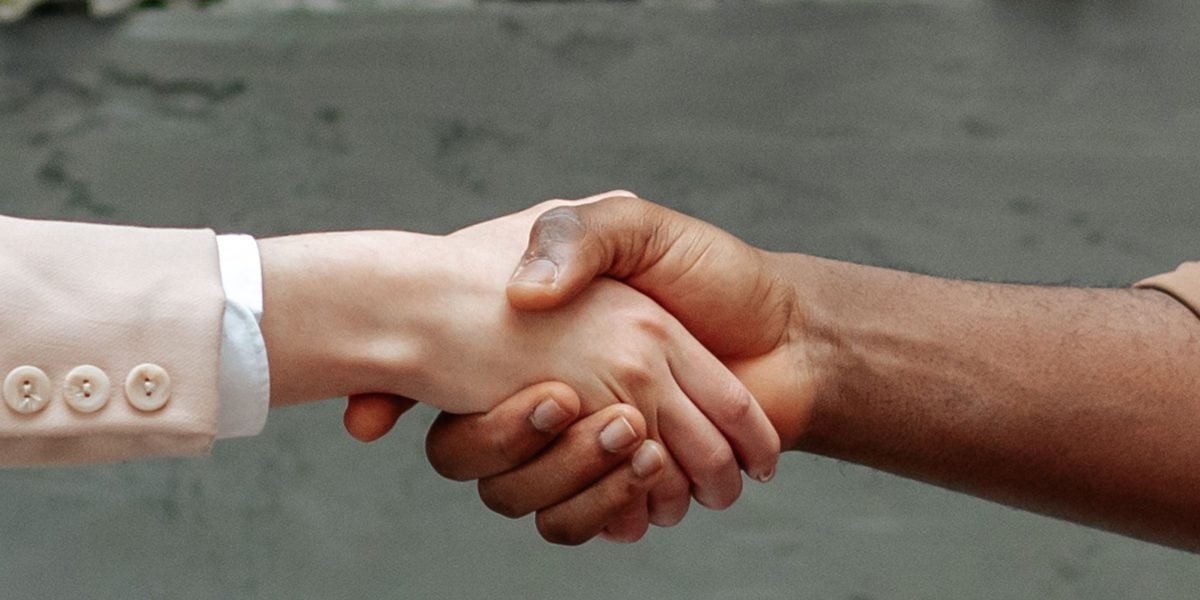 Two professionals shake hands in an office, representing career advancement and successful collaboration after achieving certification.