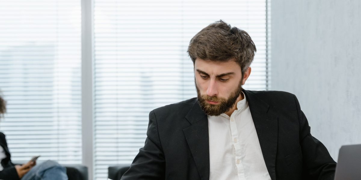 A person, representing a business owner, looks thoughtfully at a report, reflecting concern over business challenges.