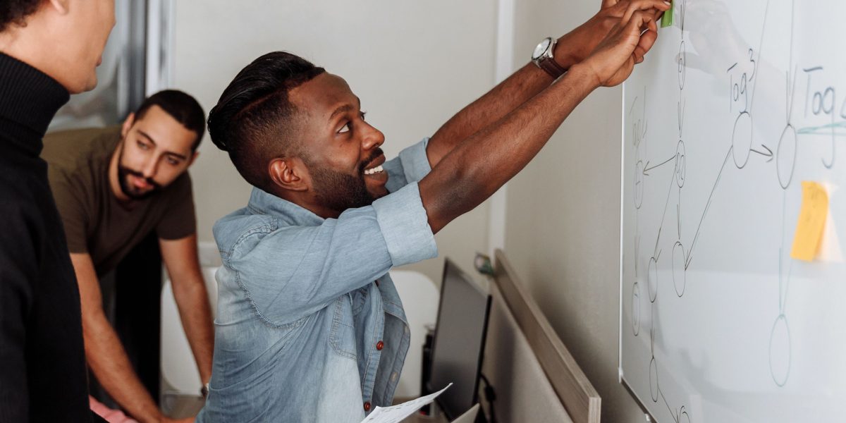 A diverse team actively collaborating, using a whiteboard to outline new strategies and organizational changes.
