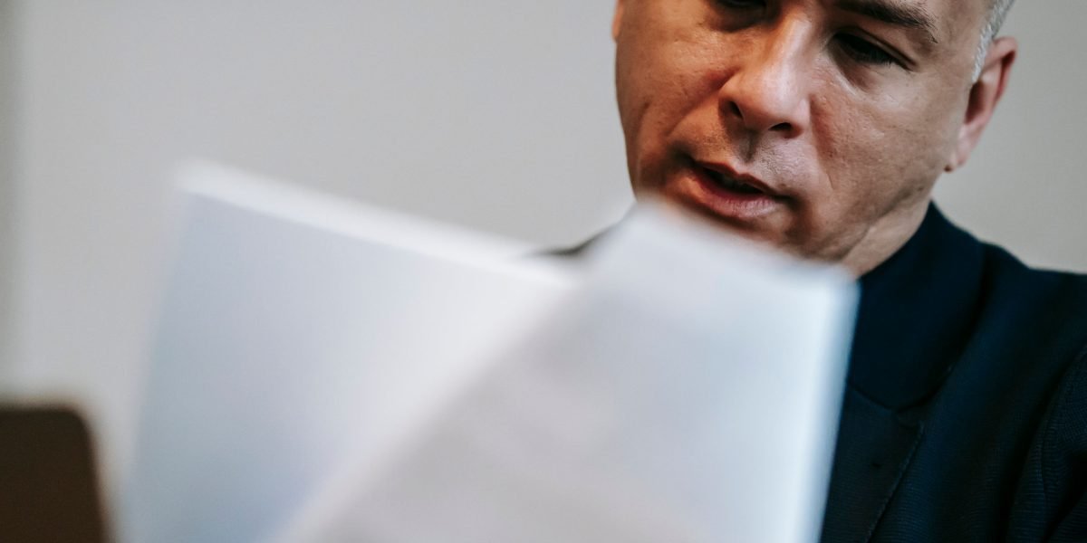 A professional meticulously examining data on documents, emphasizing the need for human oversight amidst AI risks.